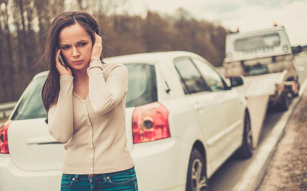 lady on a mobile phone next to a white car